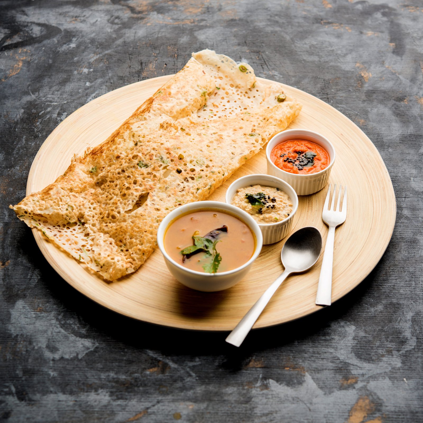 Onion rava masala dosa is a South Indian instant breakfast served with chutney and sambar over moody background. selective focus